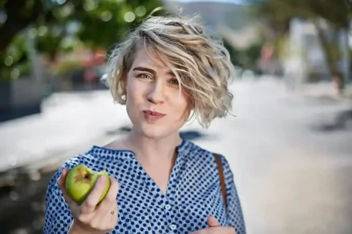 Situaciones en que no se debe comer manzana Una persona sosteniendo una manzana con gesto de duda, ilustrando las situaciones cuándo no se debe comer manzana.