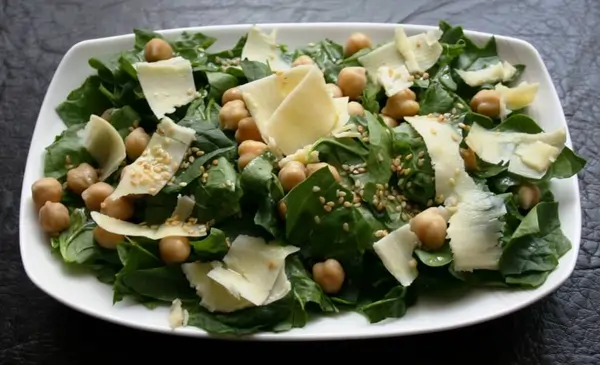 Fuentes naturales para entender para qué sirve la vitamina K Un plato con alimentos como espinacas, brócoli y queso, ilustrando para qué sirve la vitamina K y sus fuentes naturales.