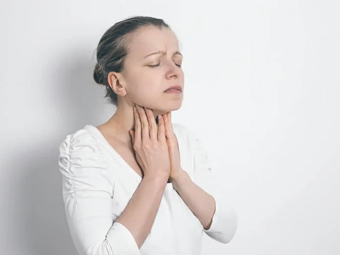 Una mujer tocándose el cuello, reflexionando sobre qué es el hipotiroidismo primario y cómo manejar sus síntomas a través de la dieta.