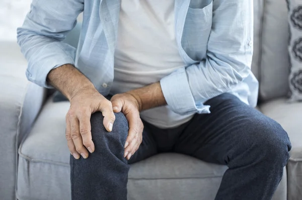 Entendiendo qué es el dolor articular en la rodilla Una persona mayor masajeando su rodilla para entender qué es el dolor articular y cómo aliviarlo de forma natural.